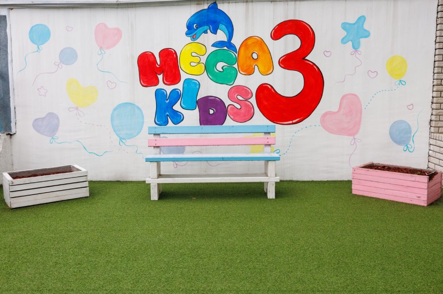 Dvorišni prostor vrtića Mega Kids 2 na Novom Beogradu sa klupom i oslikanim zidom prilagođenim deci
